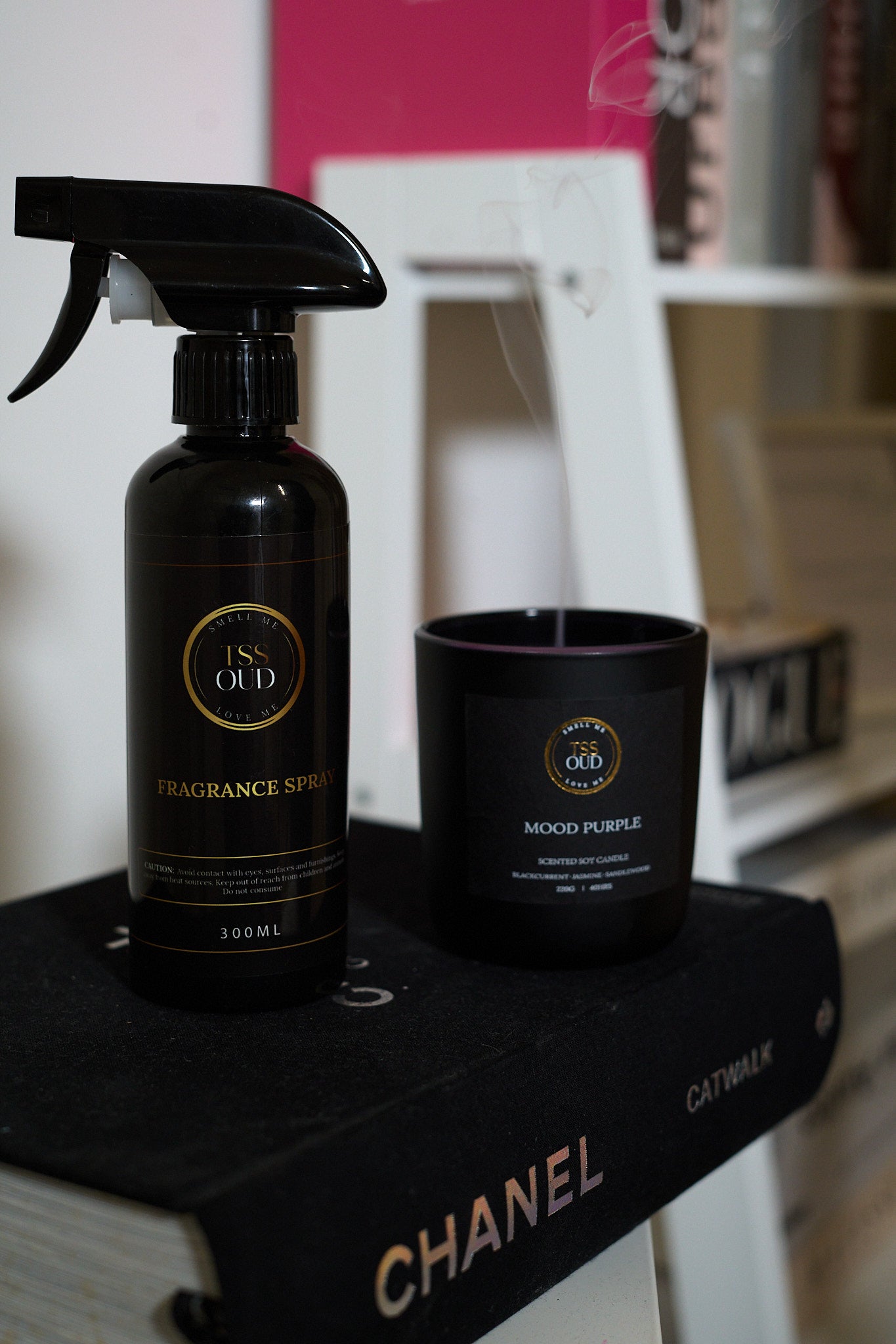 Black spray bottle and candle on a Chanel box with a blurred background